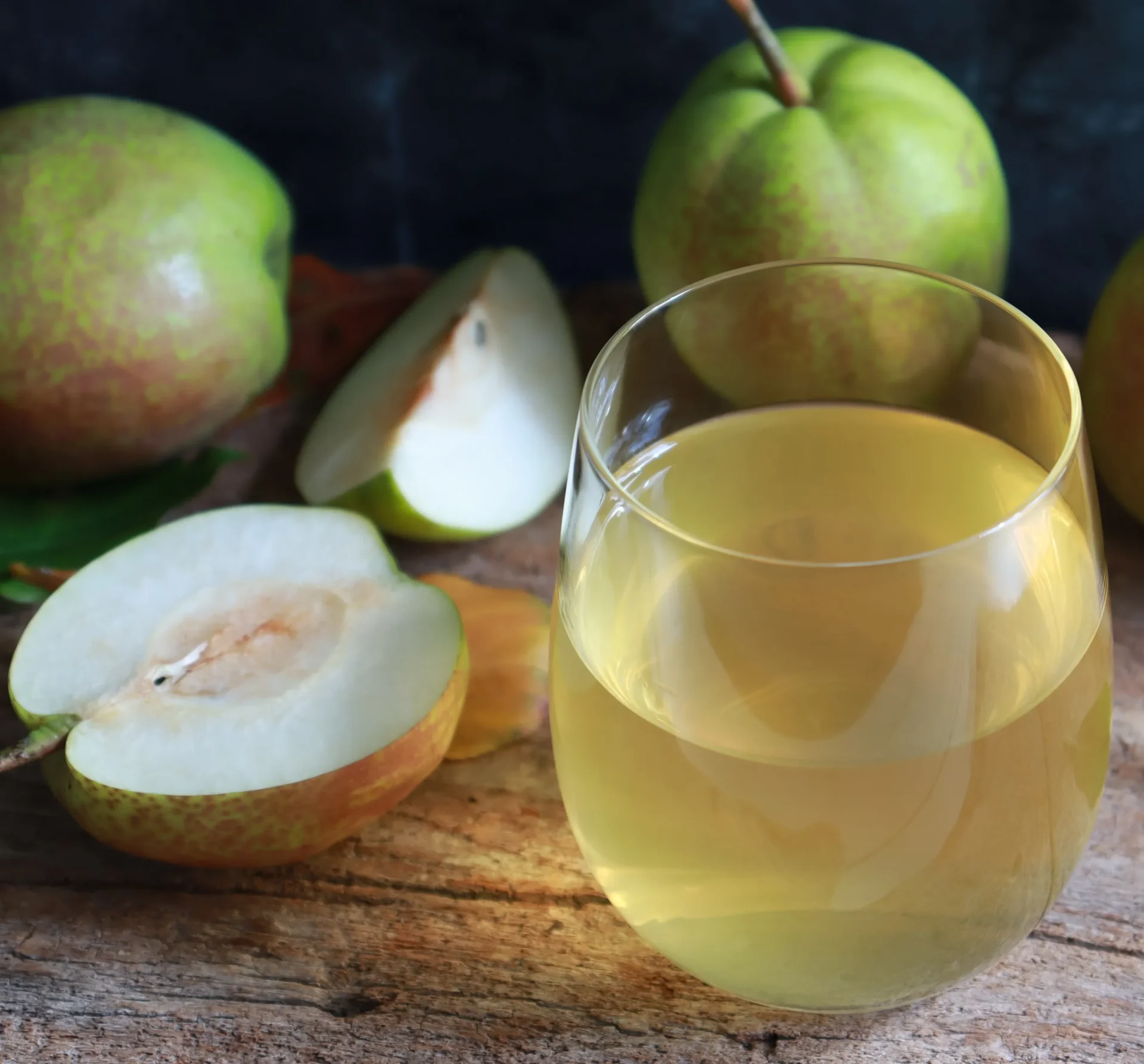 Saft in einem Glas und darum Birnen sind auf einem Holztisch